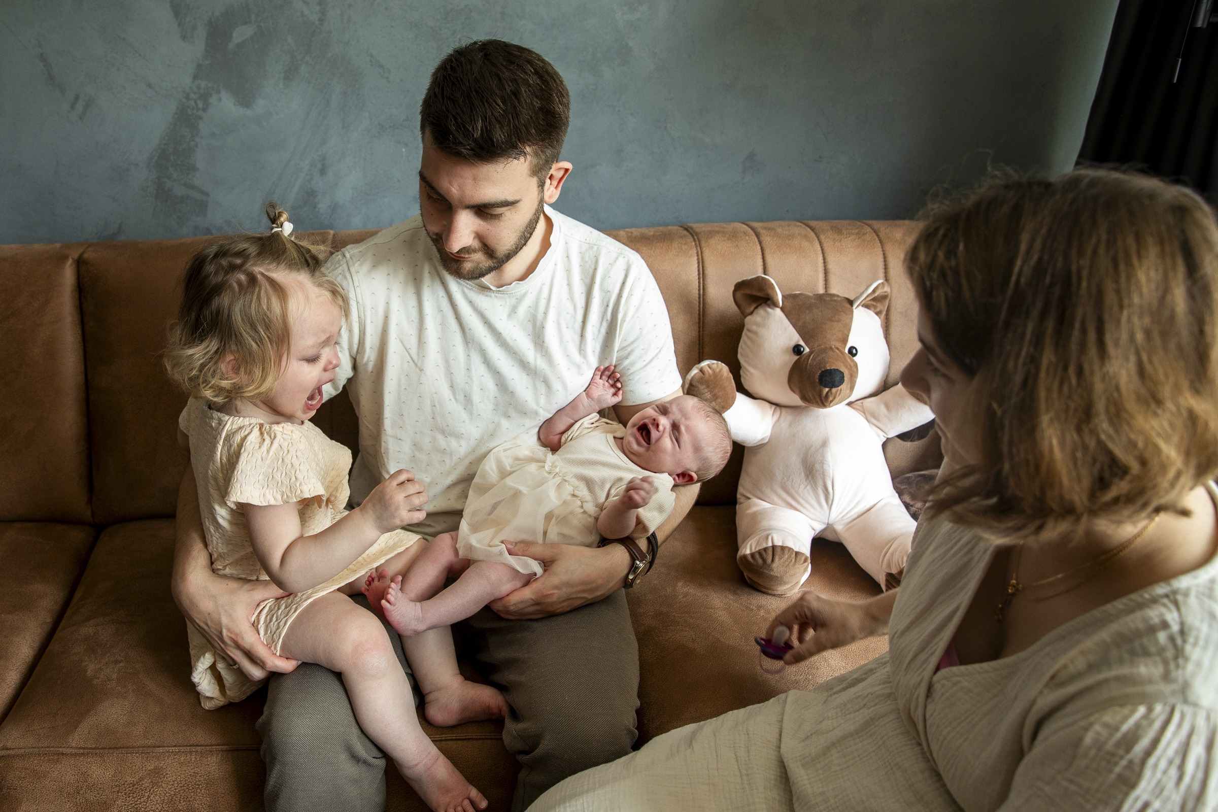 Gezin met een peuter en baby op de bank met een grote knuffel