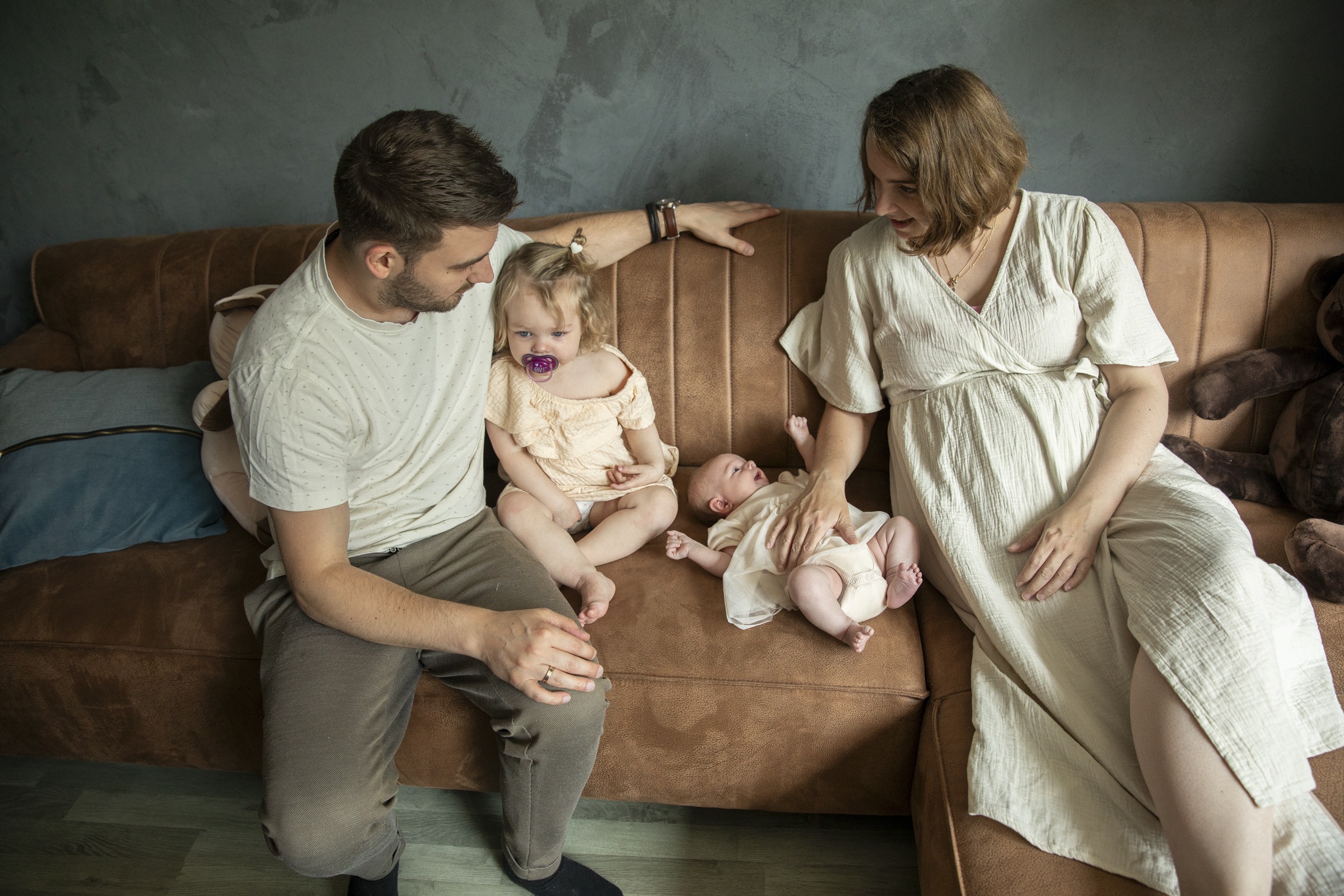 Vader,moeder, peuter en baby samen op de bank in de woonkamer