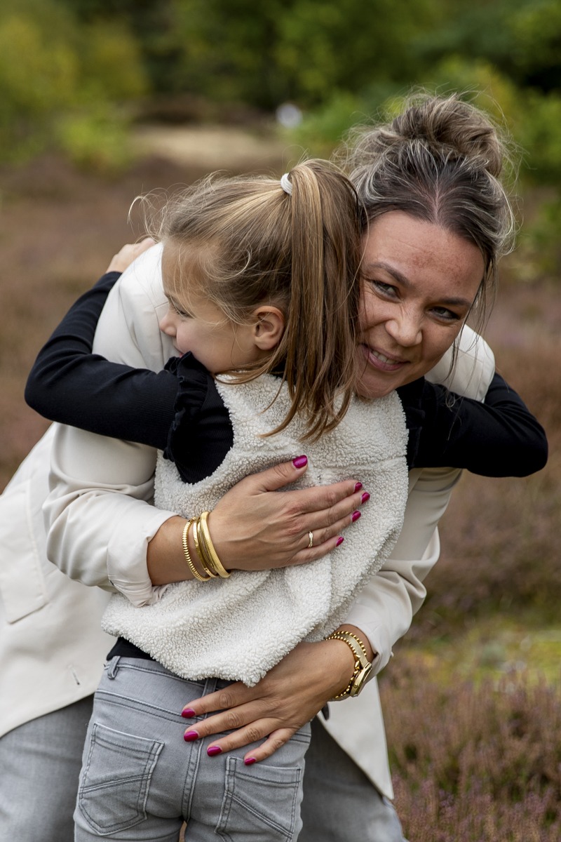 Een moeder die haar dochter knuffelt op de heide in Drenthe