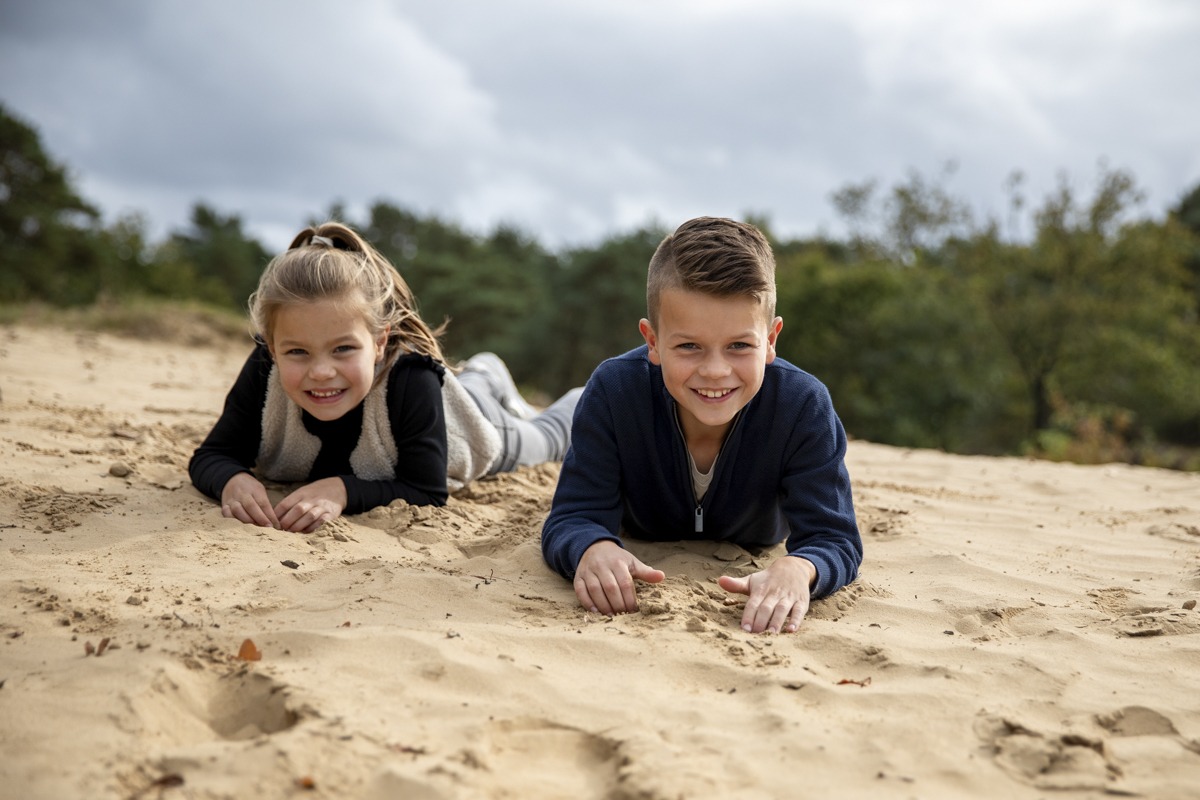 Jongen en meisje liggend in het zand van de Zeegserduinen