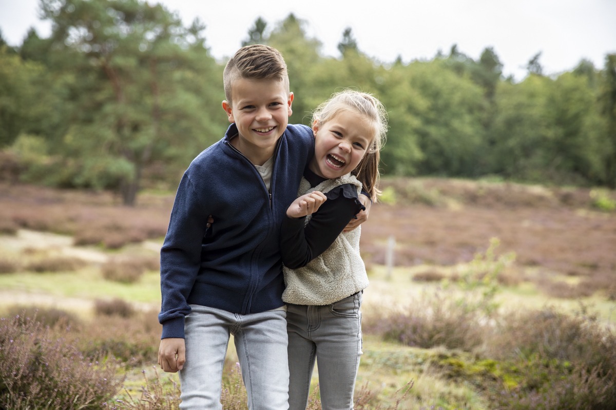 Jongen en meisje op de foto die elkaar vasthouden, die vrolijk in de lens kijken voor de foto